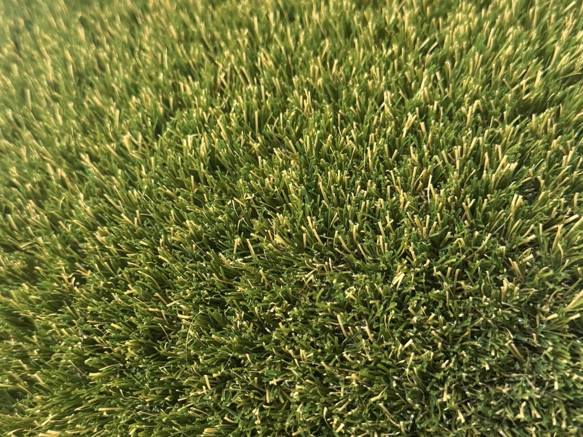 Close-up of our natural-look turf, mixed-tone green fibres with dry blades blended through, 35mm pile height.