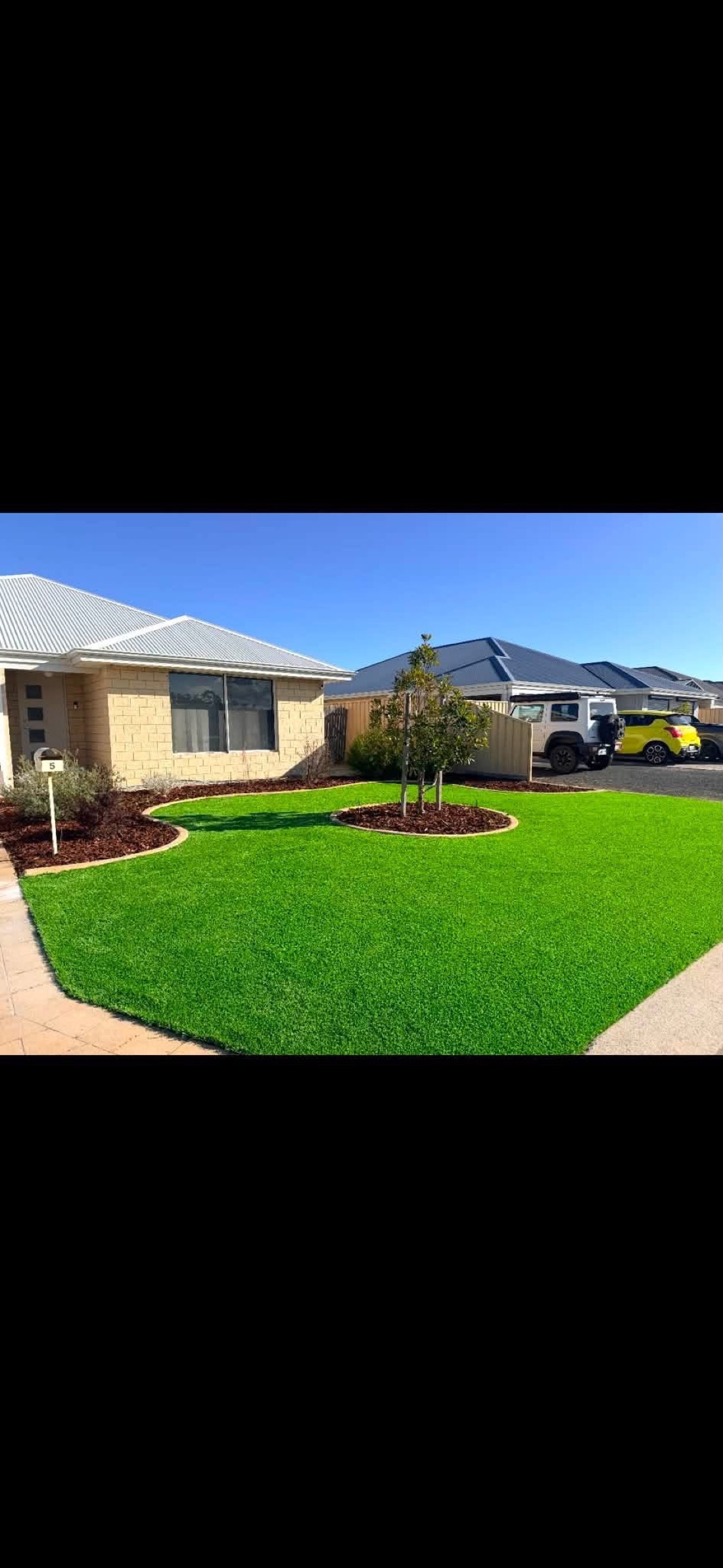 The same front yard reborn as a lush green lawn with a feature tree.
