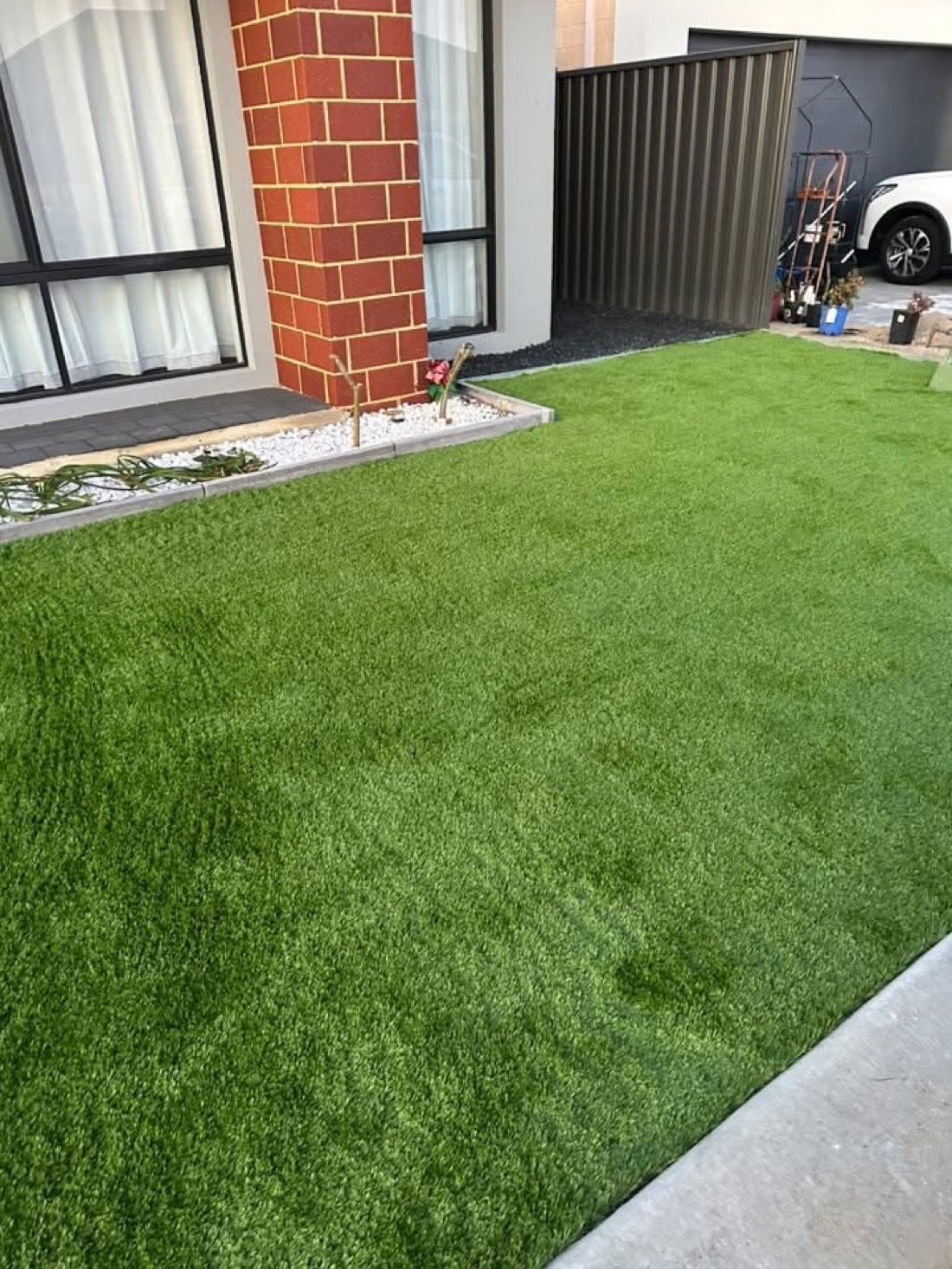 The same entry courtyard with a clean, even, lush new turf install.