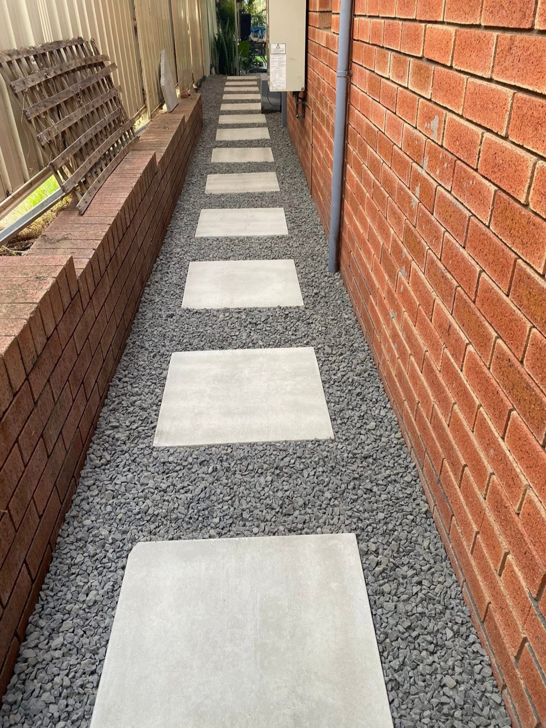 The same side passage finished with large concrete stepping stones set in dark grey gravel.