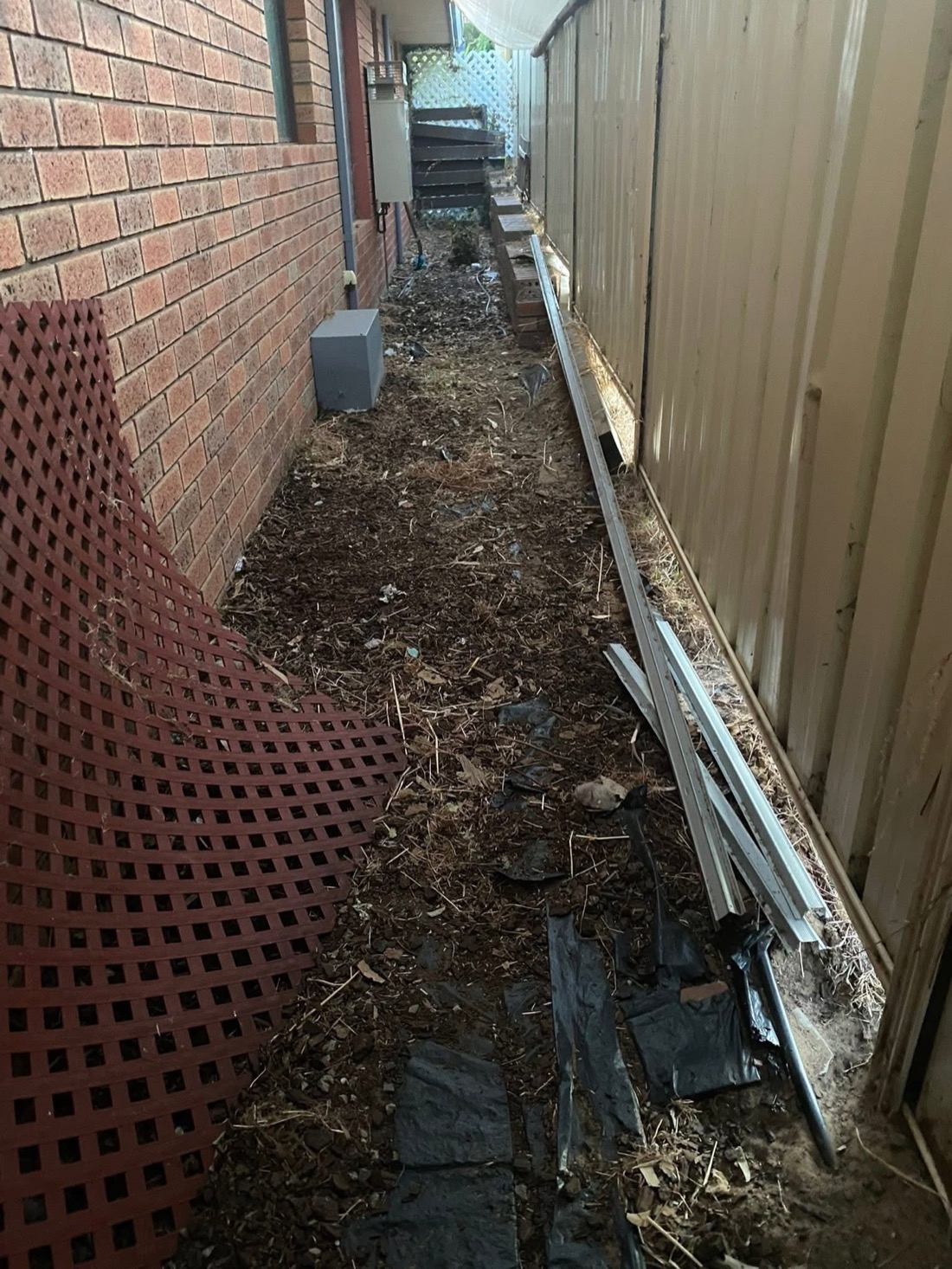 A messy side passage with dirt, debris and discarded materials.